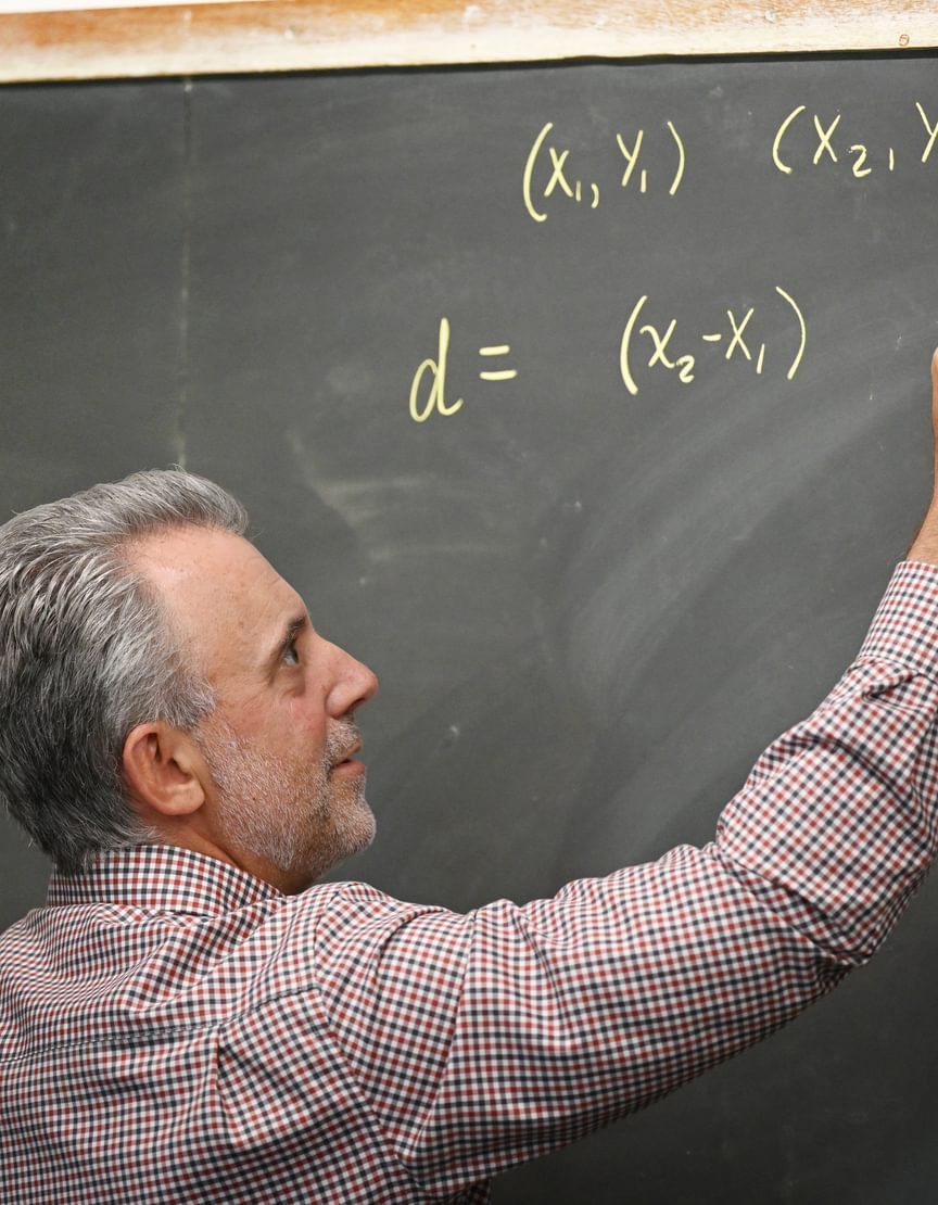 Andover faculty writing math equations on a blackboard